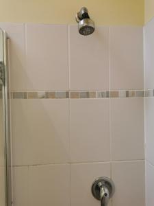 a shower with a white tiled wall and a light at The Brownlow Stables in Leighton Buzzard