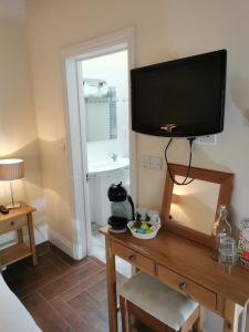 a television on top of a wooden table with a mirror at The Brownlow Stables in Leighton Buzzard +17 photos