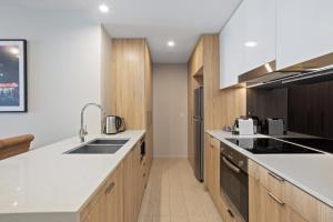 uma cozinha com bancadas brancas e armários de madeira em Cosy 1-Bed with River Views Pool Gym & BBQ em Brisbane