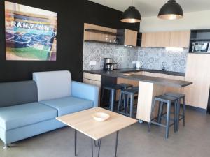 a living room with a blue couch and a kitchen at Appartement 2 ch, accès plage direct, rez-de-jardin, piscine, animaux OK - FR-1-194-284 in La Tranche-sur-Mer