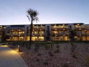 a large building with a palm tree in front of it at Appartement 2 ch, accès plage direct, rez-de-jardin, piscine, animaux OK - FR-1-194-284 in La Tranche-sur-Mer