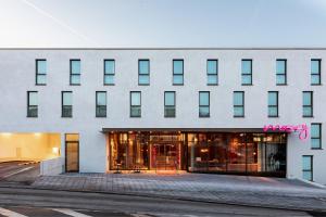 a large white building with a lot of windows at Moxy Outletcity Metzingen in Metzingen