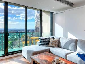 a living room with a couch and large windows at Pride CBD Skyline View 2B2B Apartment LV32 in Melbourne