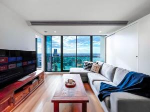 a living room with a couch and a tv at Pride CBD Skyline View 2B2B Apartment LV32 in Melbourne