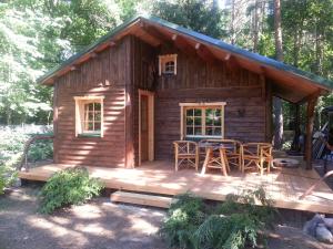 eine Blockhütte mit einem Tisch und Stühlen auf einer Terrasse in der Unterkunft Holzhaus Waldwichtel am Wald und See in Neuruppin