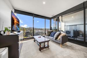 sala de estar con sofá y ventanas grandes en Center 2-Bed with Gym, Sauna, Indoor Pool & Views, en Canberra