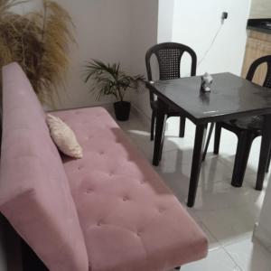 een roze bank en een tafel in de woonkamer bij Hostel Campoamor in Medellín