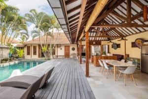 - une terrasse en bois avec une table et des chaises à côté de la piscine dans l'établissement Gorgeous 4 BR Villa in Canggu, à Tumbak Bayuh