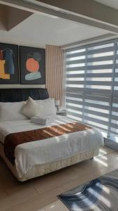 - un grand lit dans une chambre avec une grande fenêtre dans l'établissement Uptown Parksuites Tower 1 BGC, à Manille