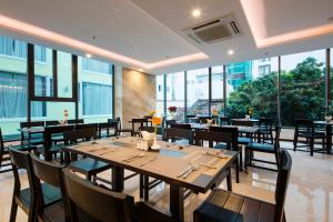 芽莊的住宿－Daisy Flower Nha Trang，餐厅设有木桌和椅子以及大窗户。
