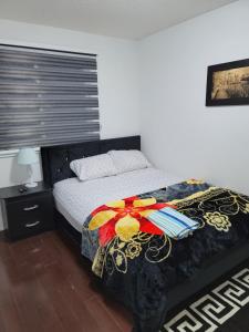 a bedroom with a bed with a comforter on it at Langston Beautiful Home in Brampton