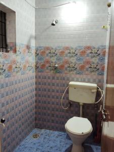 a bathroom with a toilet and a tiled wall at D'Souza Rooms in Māvalli