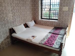 a small bed in a room with a window at D'Souza Rooms in Māvalli