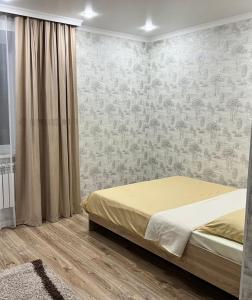 a bedroom with a bed and a wall with wallpaper at Квартира посуточно in Kokshetau
