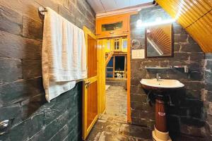 a stone bathroom with a sink and a mirror at Ashapuri Cottage near Rupi Raila Waterfall in Sainj