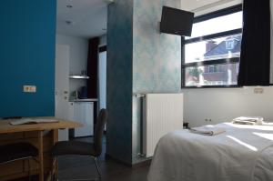 een kamer met een bed, een bureau en een raam bij Het blauwe huis in Reuver