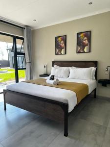a bedroom with a large bed with two pictures on the wall at SUumthing Private GuestHouse in Lebowakgomo +42 photos