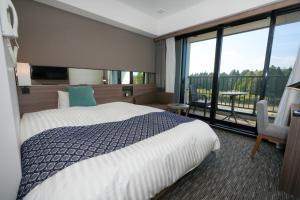a hotel room with a bed and a large window at Airport Hotel Kumamoto in Ozu