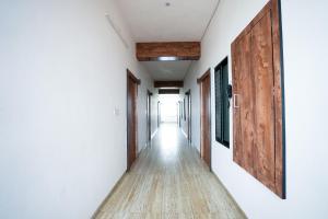 a corridor with white walls and a wooden door at ANTRA STAY by ASHOKA GROUP in Udaipur