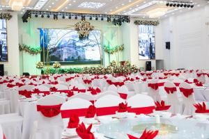 um salão de banquetes com mesas brancas e cadeiras vermelhas em Liberty Lao Cai Hotel - Events em Pho Mới