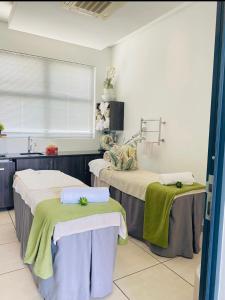 two beds in a hospital room with green towels on them at A little sanctuary in Edendale