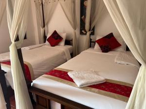2 bedden in een kamer met rode kussens bij The Royal Shilton Resort in Chiang Mai