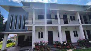 a white house with a balcony and flowers at Magizham Homestay in Kodaikānāl