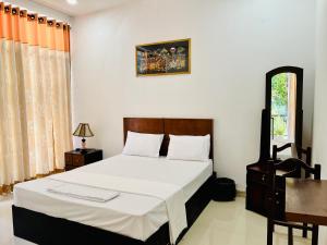 um quarto com uma cama com lençóis brancos e uma janela em Eco Resort Kandy em Kandy