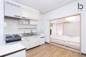 a white kitchen with a bed in a room at Dai3Kuboi - 1 BR for 4 ppl mins walk to Peace Park in Hiroshima