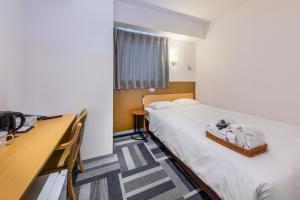 a hotel room with two beds and a desk at HOTEL NEXUS Hakata Sanno in Fukuoka