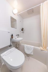 a white bathroom with a toilet and a sink at HOTEL NEXUS Hakata Sanno in Fukuoka