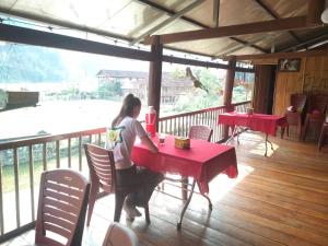 a woman sitting at a red table on a porch at Tran Xuan Homestay in Ba Be18