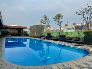 a large blue swimming pool with chairs around it at Whiz Prime Hotel Kelapa Gading in Jakarta