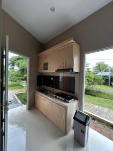 una cocina con armarios de madera y una gran ventana en Villa Cijeruk Village, en Cihideung
