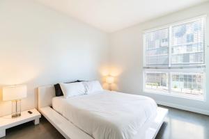 a white bedroom with a bed and a window at Brand New 2BR Luxury Apartment WeHo in Los Angeles