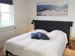 a bedroom with a bed with a blue pillow on it at 4 person holiday home in R nne in Rønne