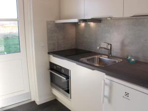 a small kitchen with a sink and a stove at 4 person holiday home in R nne in Rønne