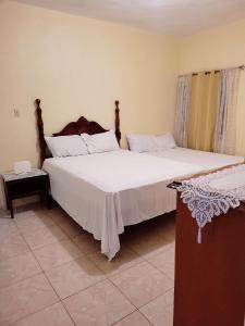 1 dormitorio con 2 camas con sábanas blancas en Jay's Chill Paradise, en Yallahs