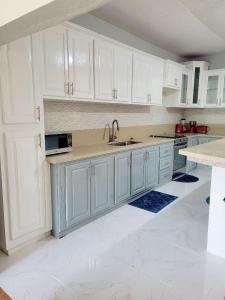 a kitchen with white cabinets and a sink at Jay's Chill Paradise in Yallahs