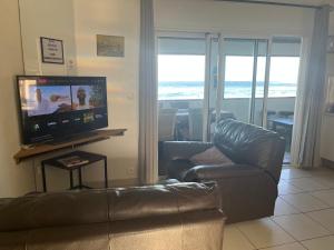 a living room with a couch and a flat screen tv at Le Cannelle in Saint-Pierre