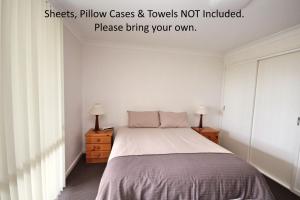 ein Schlafzimmer mit einem Bett, zwei Kommoden und zwei Lampen in der Unterkunft Frasers Cottage in Laurieton