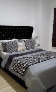 ein Bett mit schwarzen und weißen Kissen darauf in der Unterkunft 5-Star Luxury Suite, Labone in Accra
