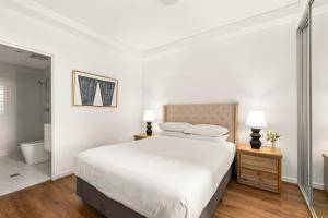 una camera bianca con un grande letto e un bagno di Stylish 2-Bed, 2-Bath with Parking in Lane Cove a Sydney