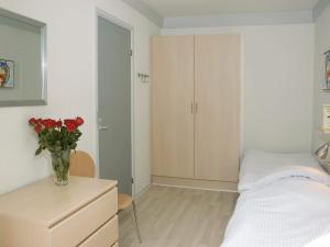 1 dormitorio con 1 cama y un jarrón de rosas rojas en 4 person holiday home in Hasle, en Hasle