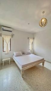 a white bedroom with a large bed and a lamp at Beach Apartment 4 Passi Residence in Watamu