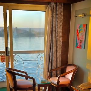 2 Stühle vor einem Fenster mit Aussicht in der Unterkunft Nile CRUISE NPS Every Monday from Luxor 4 nights & every Friday from Aswan 3 nights in Assuan