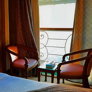 a bedroom with two chairs and a bed and a window at Nile CRUISE DELUXE ASWAN & LUXOR in Aswan