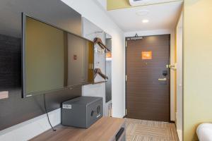 Zimmer mit einem TV an einer Wand neben einer Tür in der Unterkunft Hotel Sanrriot Osaka honmachi - Vacation STAY 21479v in Osaka
