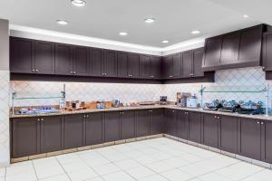 a kitchen with dark brown cabinets and white tiles at Residence Inn by Marriott Yonkers Westchester County in Yonkers