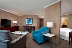 een hotelkamer met een bed en een blauwe stoel bij Sheraton Cavalier Calgary Hotel in Calgary